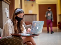 Student wearing mask while looking at laptop