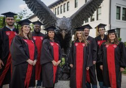 First graduating class of students from the Bachelor of Arts in Liberal Studies degree completion program in their regalia near the hawk statue, May 2023.