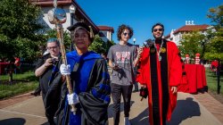 President Koppell walking toward the amphitheater in regalia being interviewed