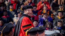koppell in amphitheater speaking to regalia-clad faculty