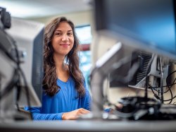 Woman poses for the camera while sitting at a desktop computer