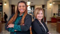 two women stand back to back