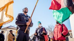 Police officer holds a red, black and green flag.