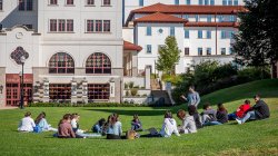 students attending class outside, sitting on lawn
