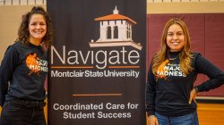 two women standing next to a banner
