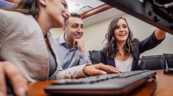 Three people sitting in front of a computer