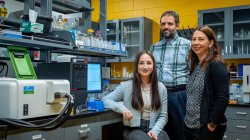 Three people pose in a science lab.