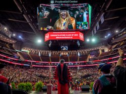 President Koppell on stage with the Prudential Center jumbotron above him showing gradutes in the crowd