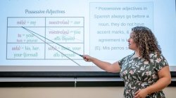 A woman points to a screen with Spanish adjectives on it.