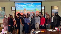 Group of people pose in front of projector screen