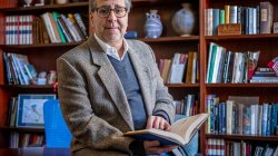 Mark Rotella holding a book and sitting in a libray.