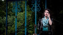 Woman on her phone in front of a fence.