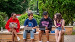 Group of 4 students discussing with each other on campus.