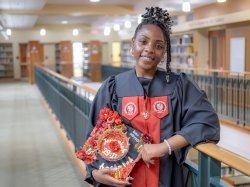 Lataiva Balmer, a psychology major graduate of Bloomfield College of Montclair State University, is shown in the college library wearing her cap and gown on the Bloomfield campus.