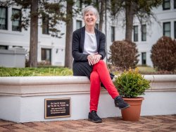 Lise Green sitting on a stone bench. Her name plaque is attached to the bench.