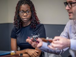 tudent Nikki Morgan-Ike observes as Professor Christopher Donoghue demonstrating a robot built by household items.