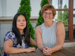 Two women sitting side by side in a courtyard on the Montclair State University campus.