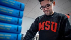 Student organizing a stack of textbooks.