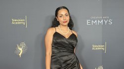 Raciely Rodriguez, in a black evening dress, stands before a backdrop showing Television Academy and Emmy logos.