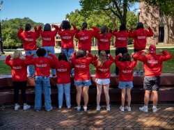 The full social media ambassador team poses, facing away from the camera, showing their team shirts
