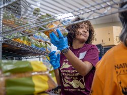 Student volunteer in pantry holding a loaf of bread