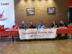 Student volunteers sitting at a table on at an event.