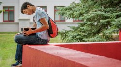 student reading a book on the quad in summer