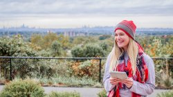female student in winter clothes on campus with view overlooking NYC skyline