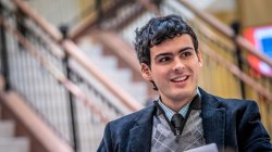 Student in vest and coat in the lobby of the Feliciano School of Business building