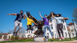 Four students photographed jumping in the air, frozen mid-jump