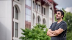 student in gray tee in front of university hall