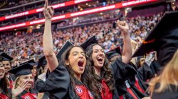 two graduates cheering in the crowd at Commencement