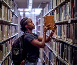 student picking book from library shelf