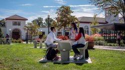 three students seated at outdoor table on Montclair campus