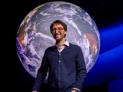 Marc Favata standing in front of a mural of the Earth