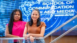 Two students stand before a Montclair State University School of Communication and Media screen.