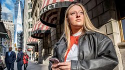 Emma Haskell stands on a sidewalk in lower Manhattan holding her phone.