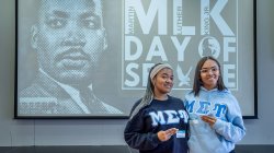 Two sorority members stand before a Martin Luther King Jr.’s Day of Service screen.