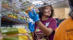 Student volunteer in pantry holding a loaf of bread