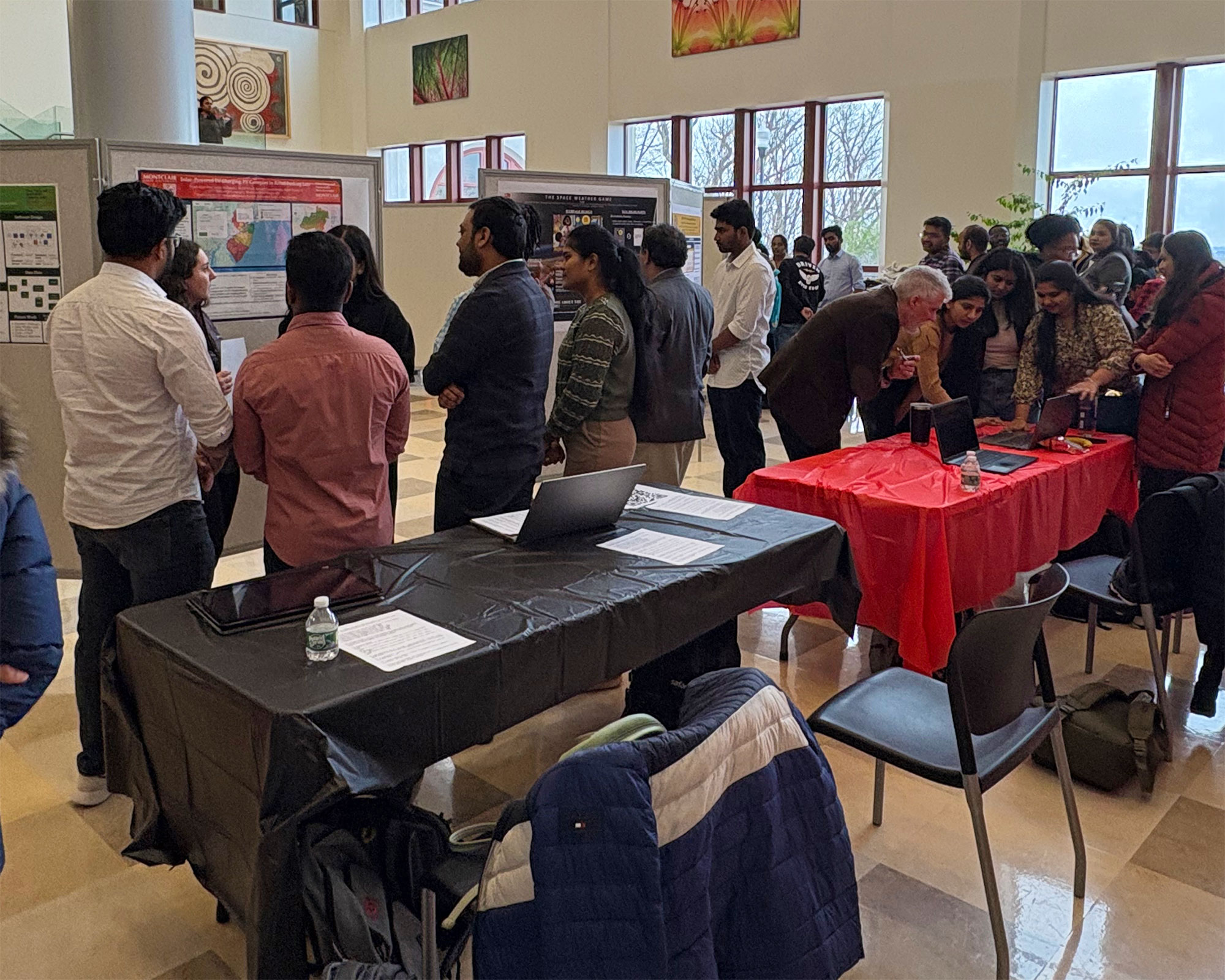guests looking at and talking about posters with students at Capstone Showcase