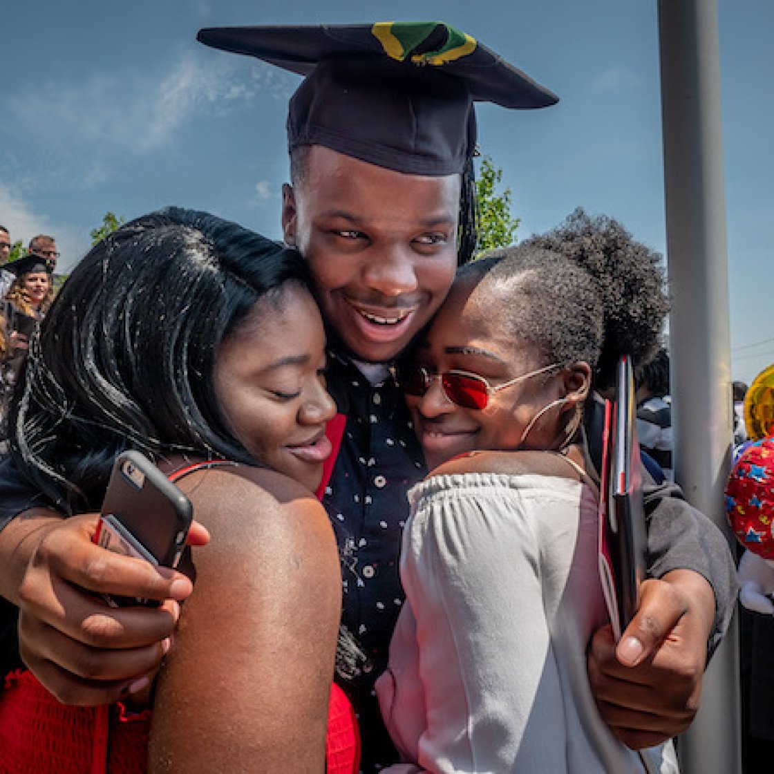 A graduate hugging his family
