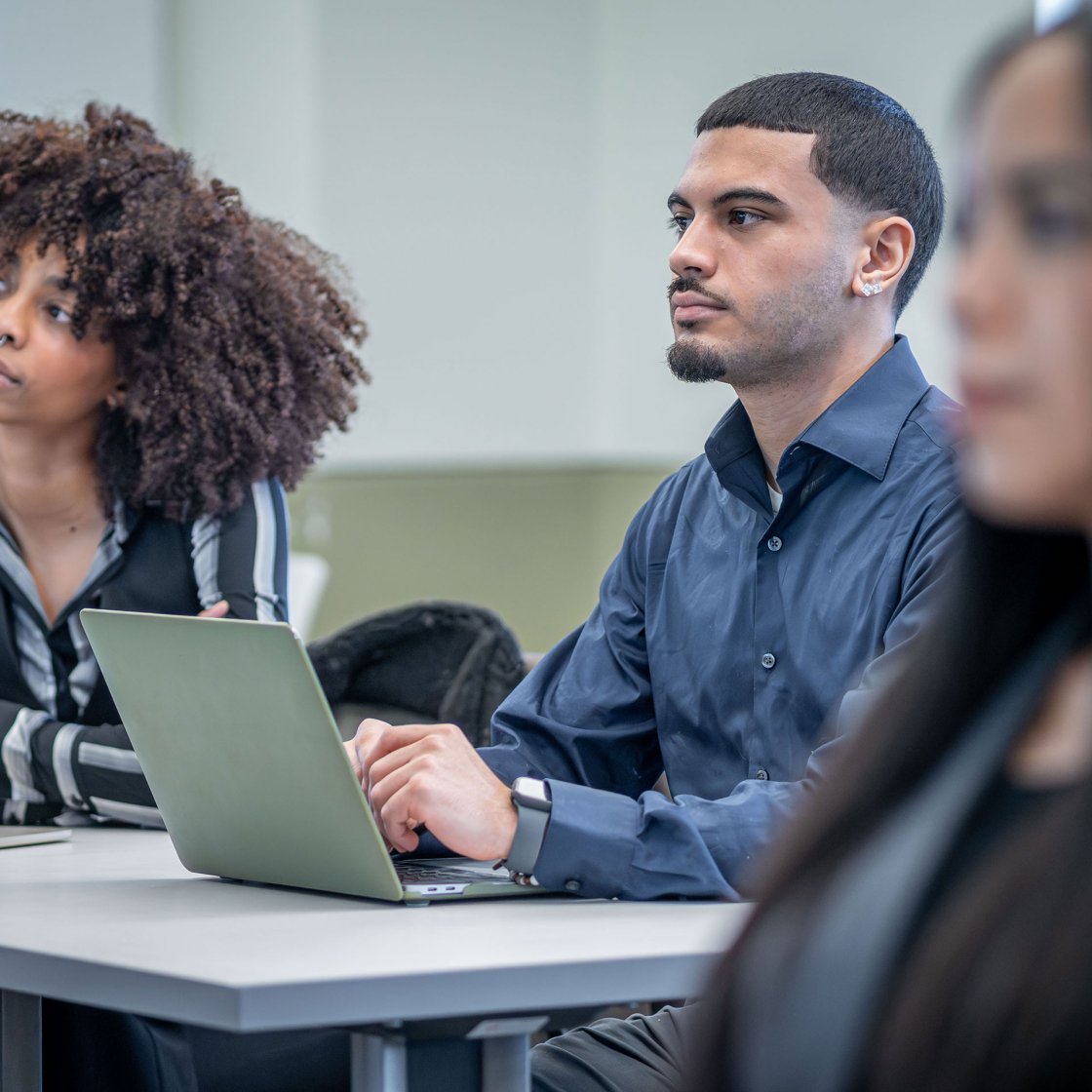 Business school students sitting in lecture hall with laptops