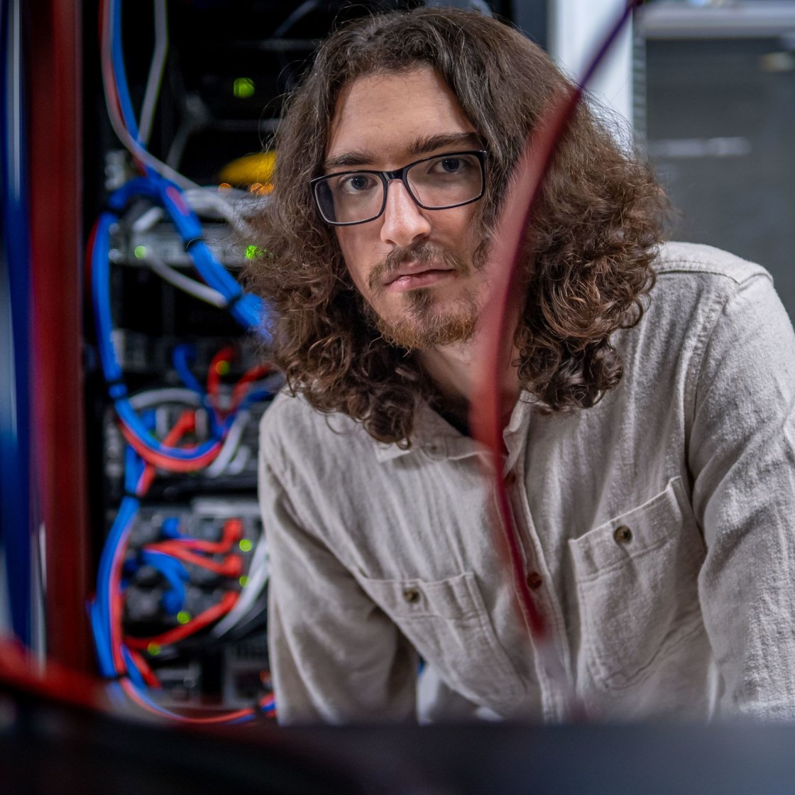 Joseph David Quinn-Vitabile working in a technology lab, surrounded by computer servers and cables.