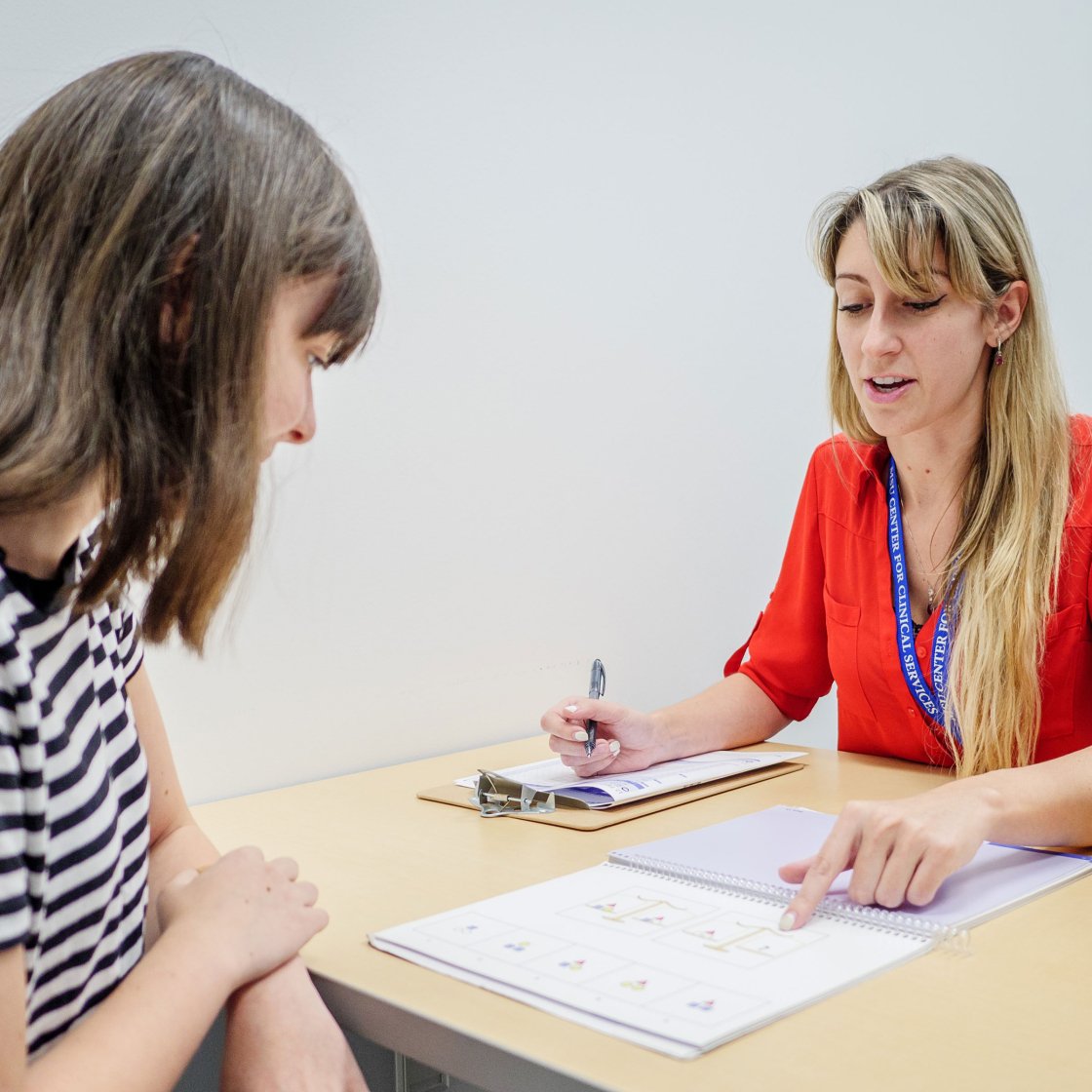 Clinical psychology student worker speaking with a person over a desk