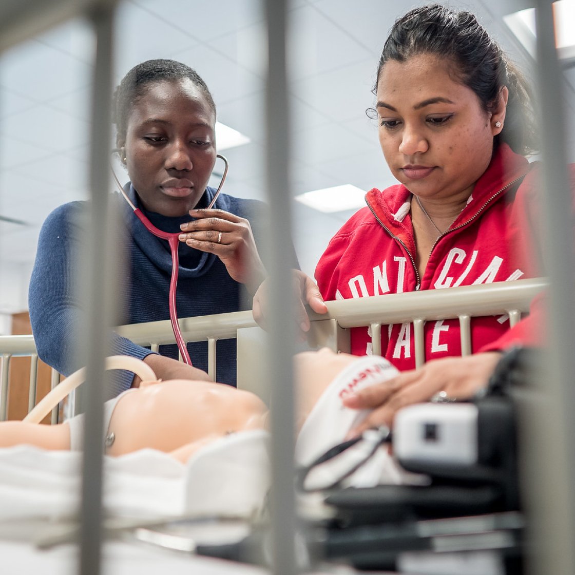 Two nursing students use an infant mannequin for realistic medical simulations.