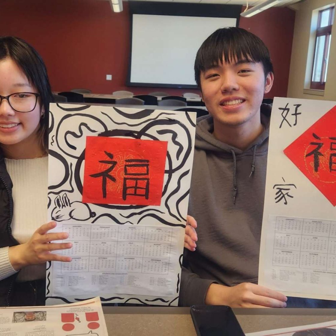 Students showing calendars written with Chinese blessings at a Chinese Calligraphy Workshop.