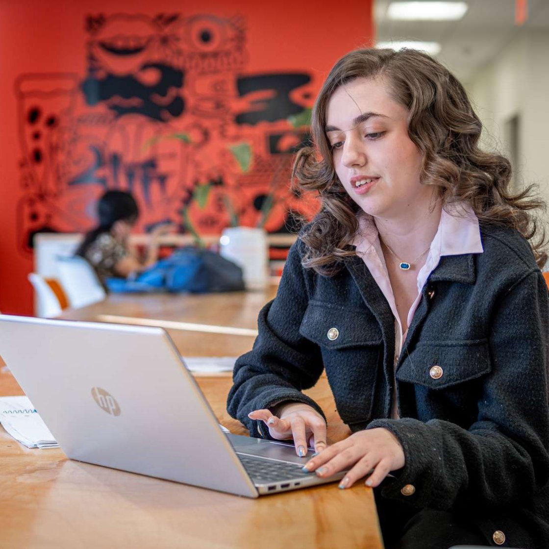 Student in business attire working on a laptop.