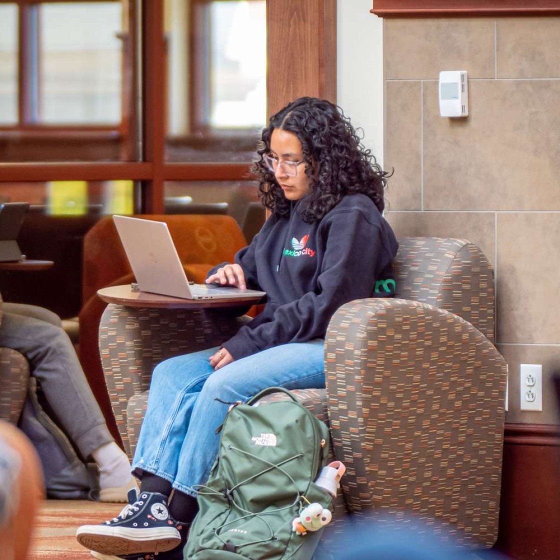 Student studying on laptop in lounge.