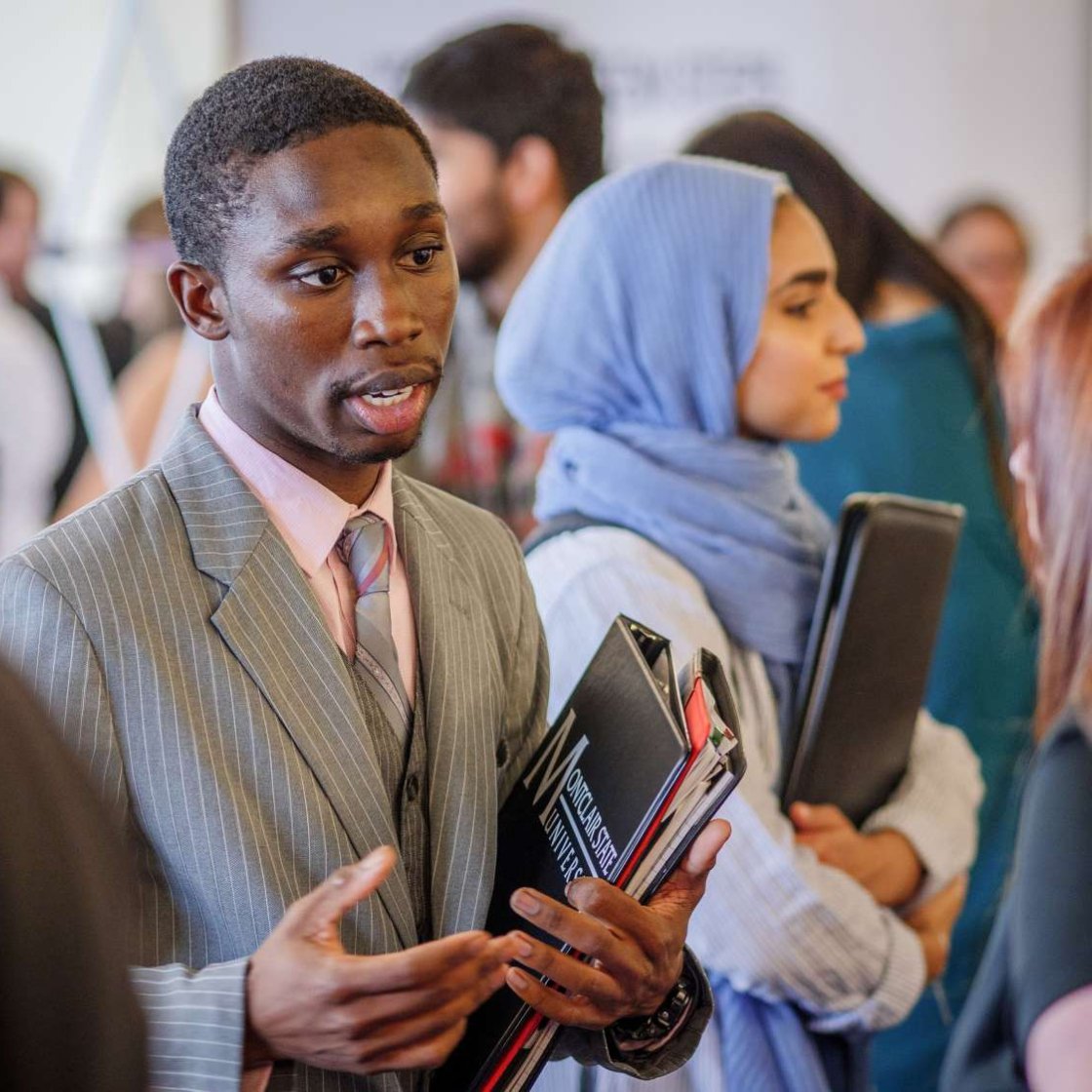 Student in business attire, speaking to a company representative at job fair