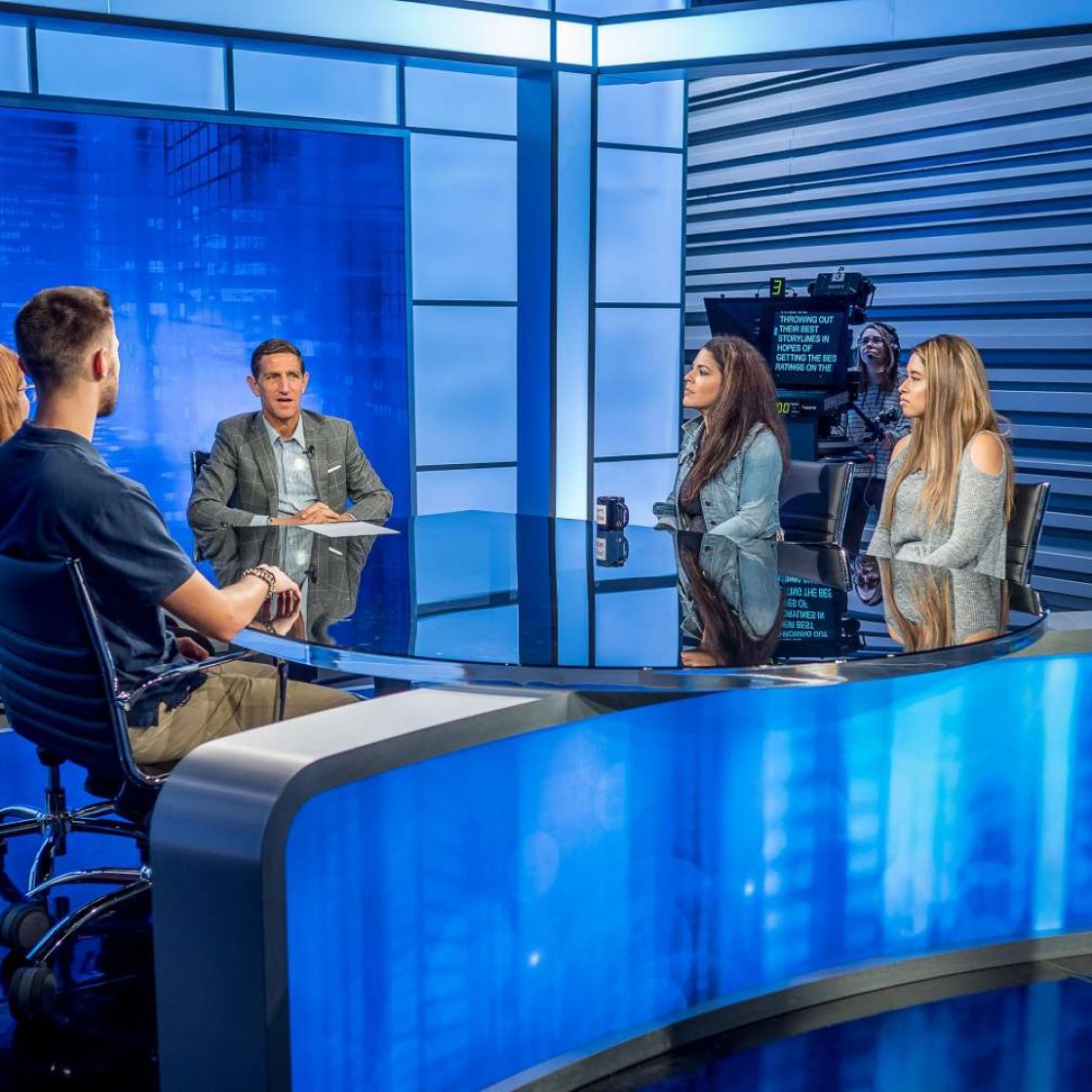 Students interviewing a guest at a news desk